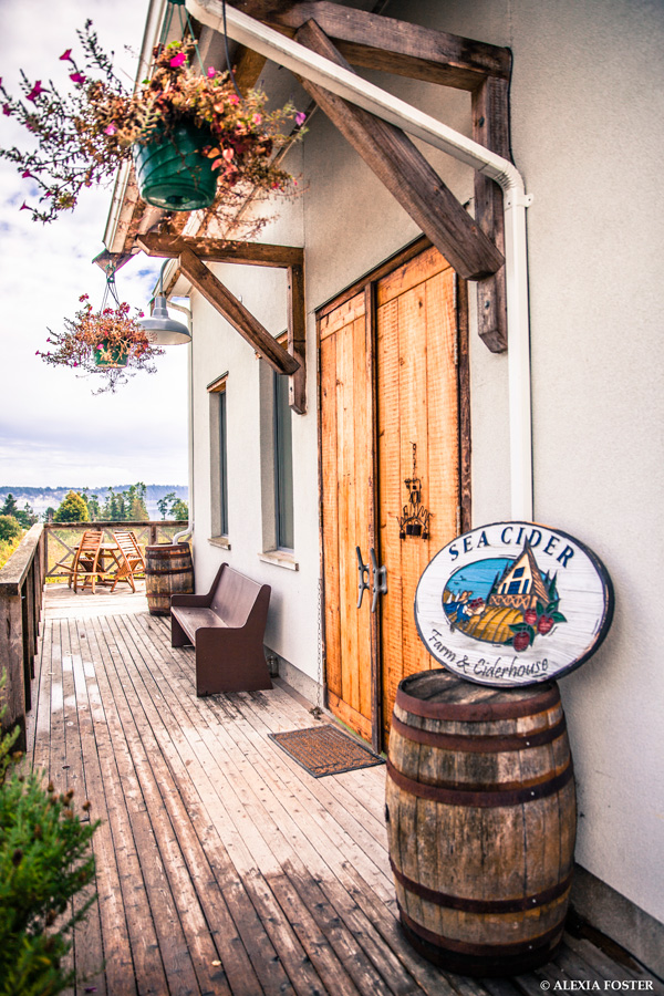 Photo of the front doors of Sea Cider cidery with a background of country scenery and distant ocean