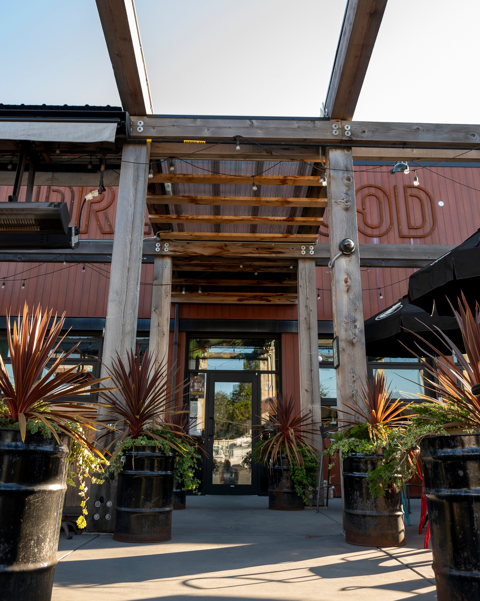 Photo of the entrance to a patio with a wooden roof and large potted plants