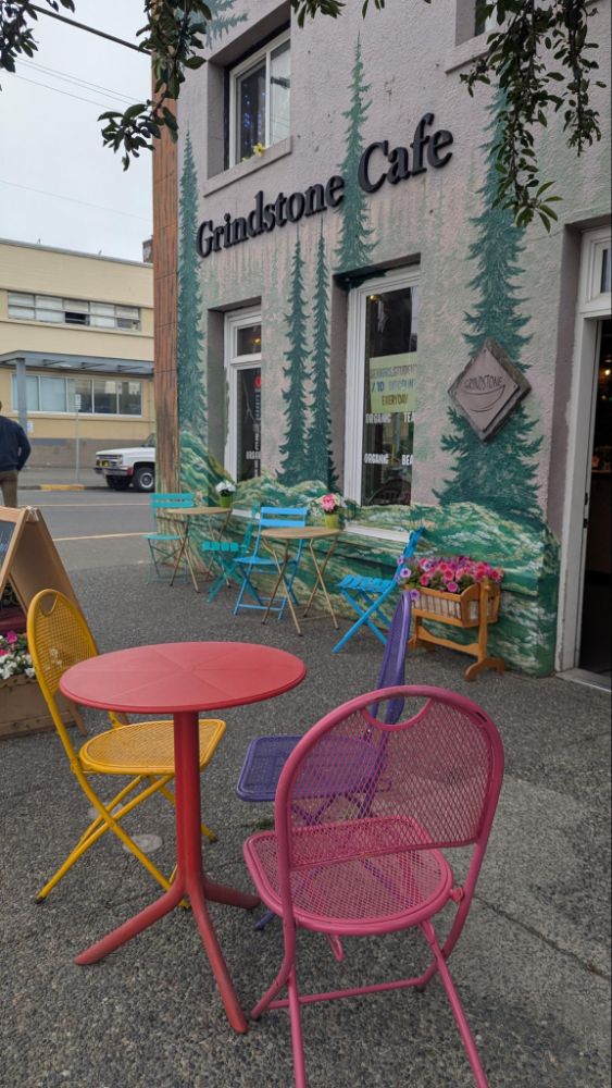 Photo of colourful metal chairs and patio tables in front of a forest mural