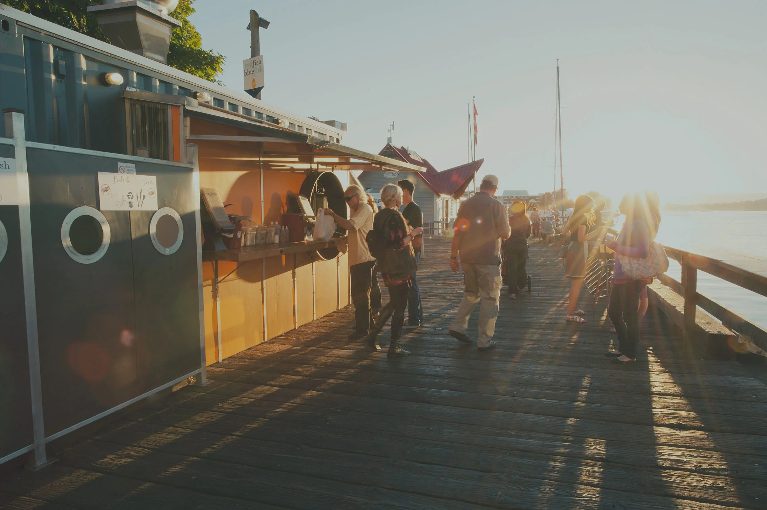 Photo of people ordering at a take-out window on a dock in the sunset